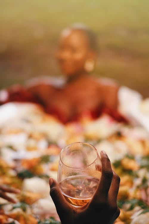 Hand Holding Glass and Woman behind