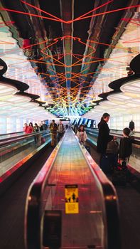 A vibrant, illuminated walkway in an airport with travelers, creating a modern and symmetrical view.