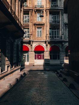 Sunlit alley in Istanbul with historic architecture, red awnings casting dramatic shadows.