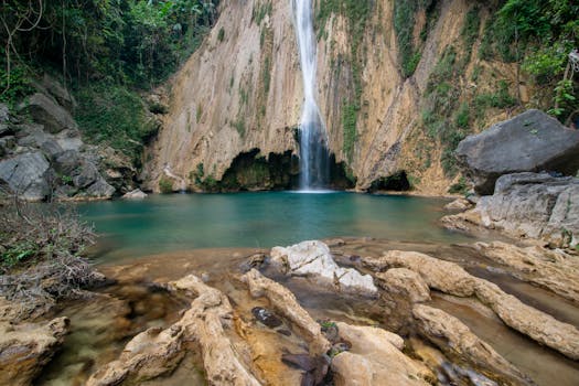 Serene waterfall flowing into a turquoise pool surrounded by rocky landscape, perfect for nature lovers.