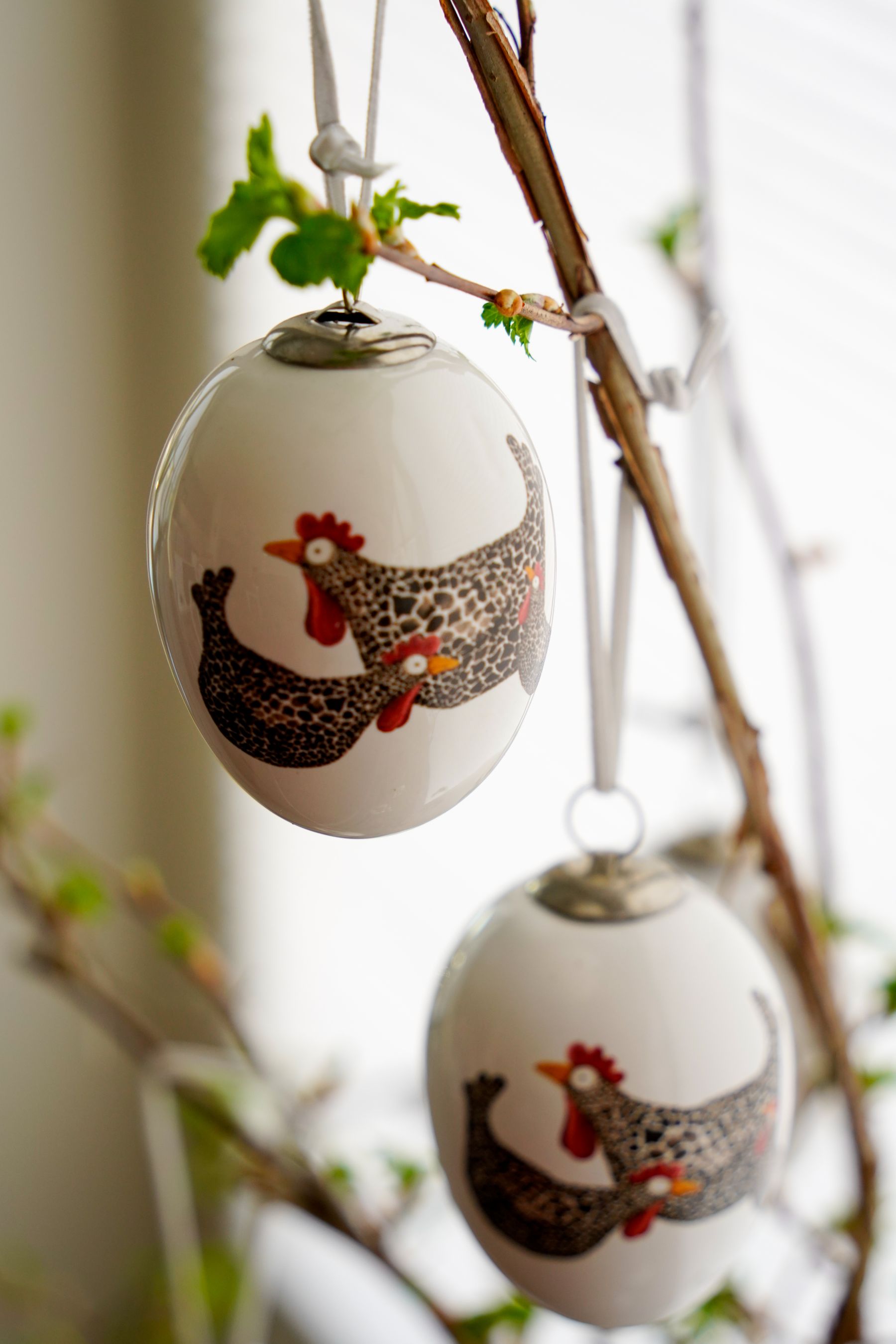 Decorated Easter eggs hanging from a simple spring branch indoors