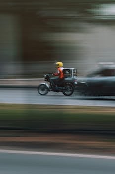 Fast-moving motorbike with rider in helmet zooming down a street in Abuja, Nigeria.
