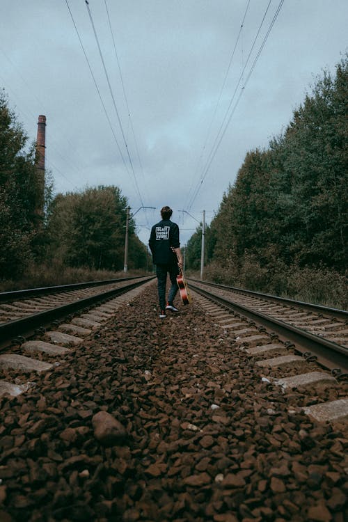 Man with Guitar Walking on the Railroad