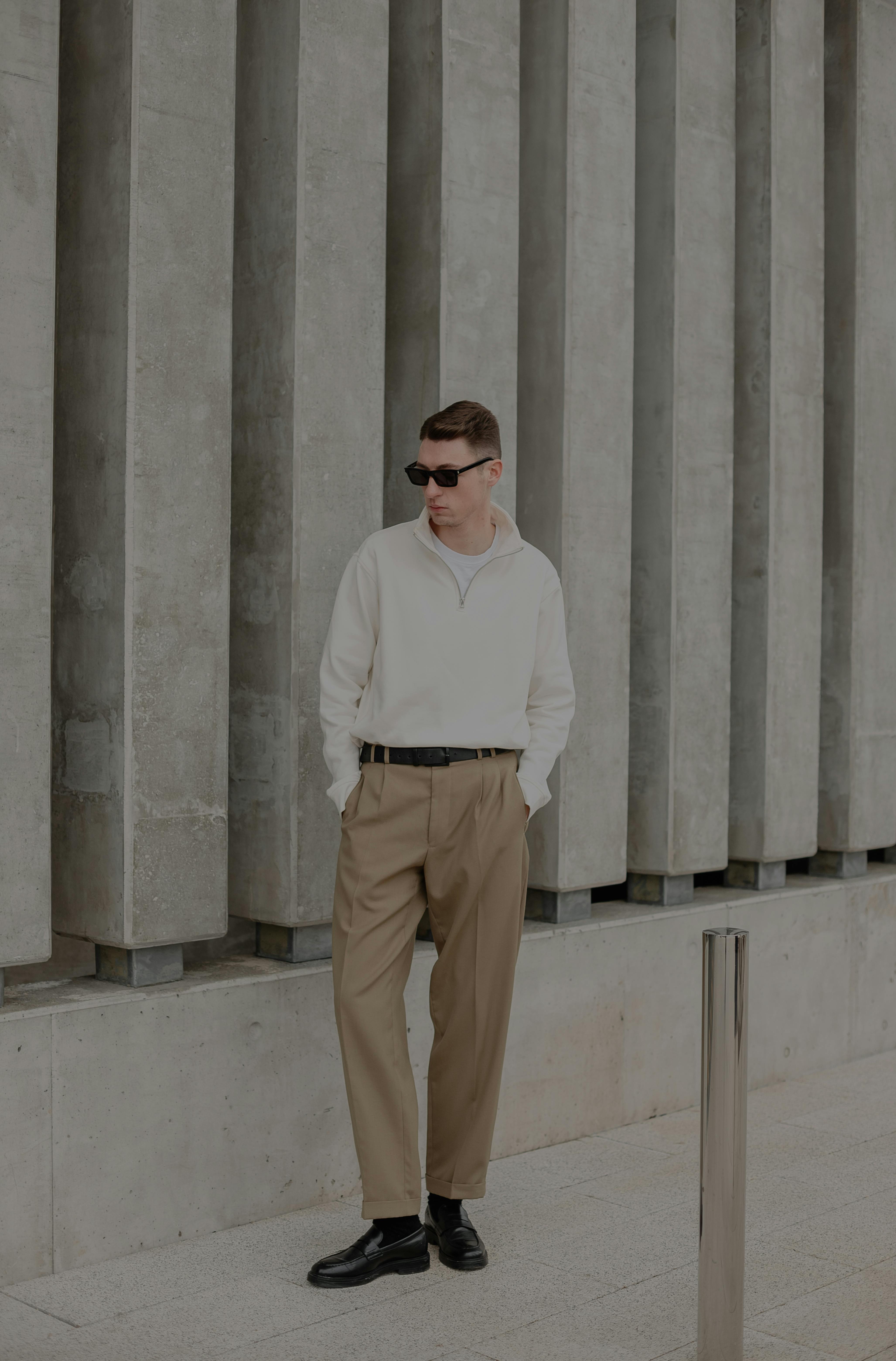 Young man in sunglasses standing by modern columns.