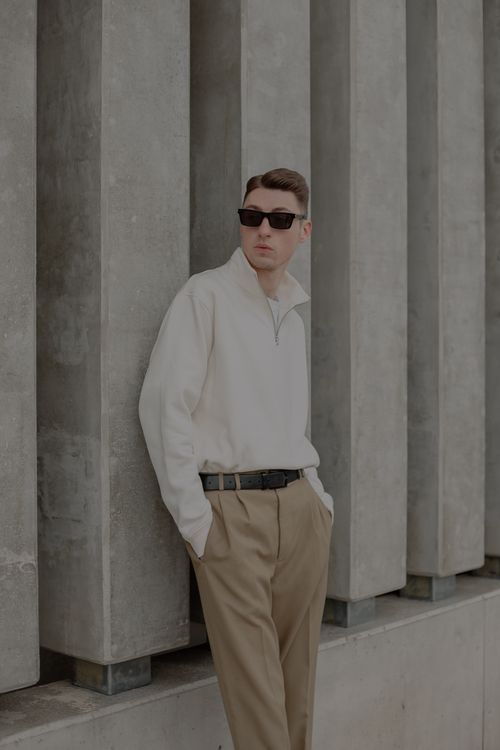 Free Man wearing sunglasses and smart casual attire leaning on concrete pillars. Stock Photo