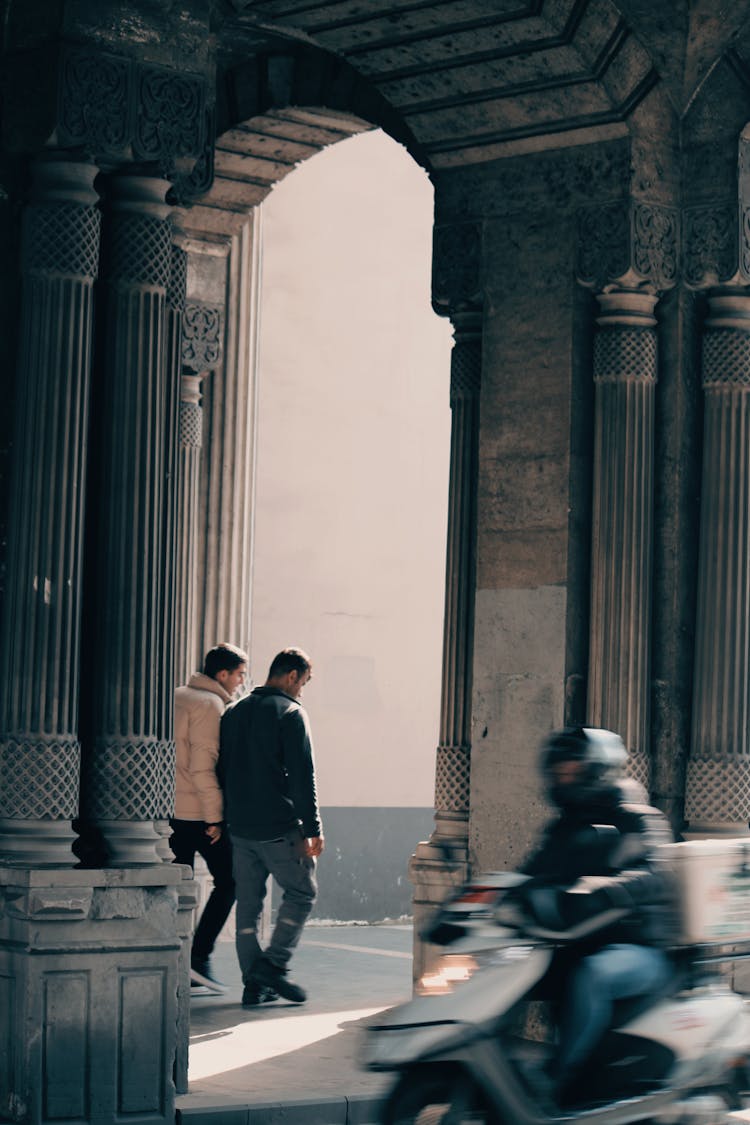 Men And Scooter Near Building Columns