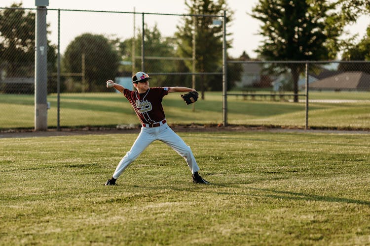 Boy In Uniform Playing Baseball On Field