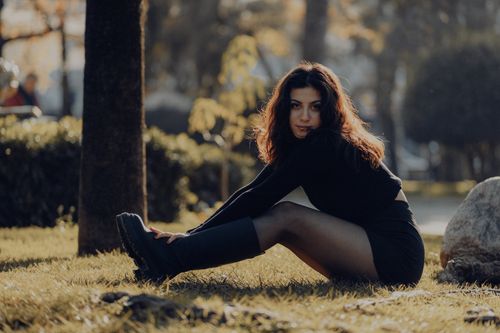 Free Young woman in black outfit poses in a sunlit park, showcasing modern fashion and natural beauty. Stock Photo