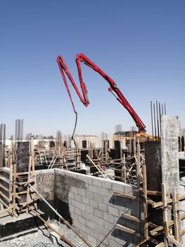 Concrete pump at a construction site under a clear sky in Al Dhaid, UAE. Urban development in progress.