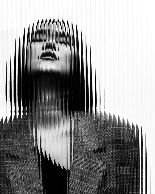 Black and white portrait of a woman with a distorted vertical line effect creating a surreal view.