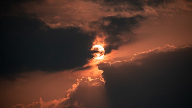 Captivating sunset scene with sun peeking through dramatic clouds, creating a vivid and moody atmosphere.