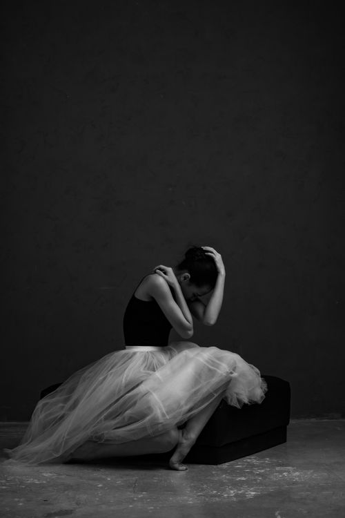 Free Black and white portrait of a thoughtful ballerina seated elegantly with a graceful pose. Stock Photo