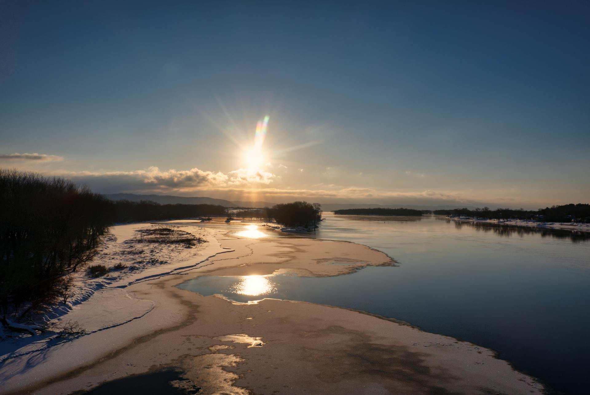 Scenic winter sunset over a river with icy banks and vibrant sky near Wabasha, Minnesota.