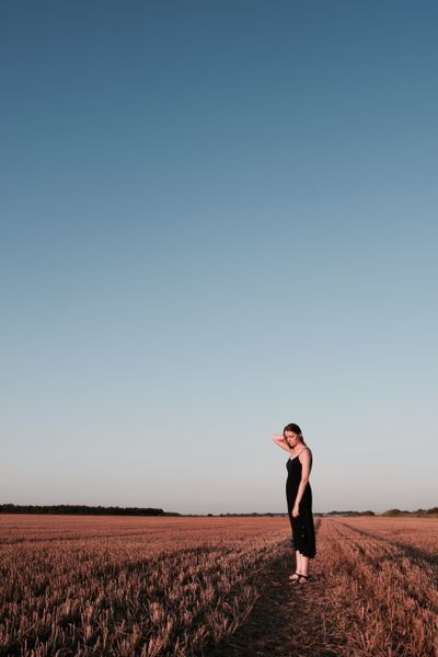 Woman standing in a field at dusk — photo by Lorete M on Pexels