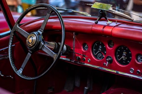 Free Close-up view of a vintage Jaguar XK150 red car interior showcasing the steering wheel and dashboard. Stock Photo