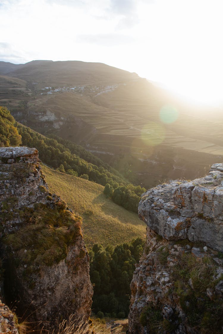 Sunlight Over Rocks And Valley Behind