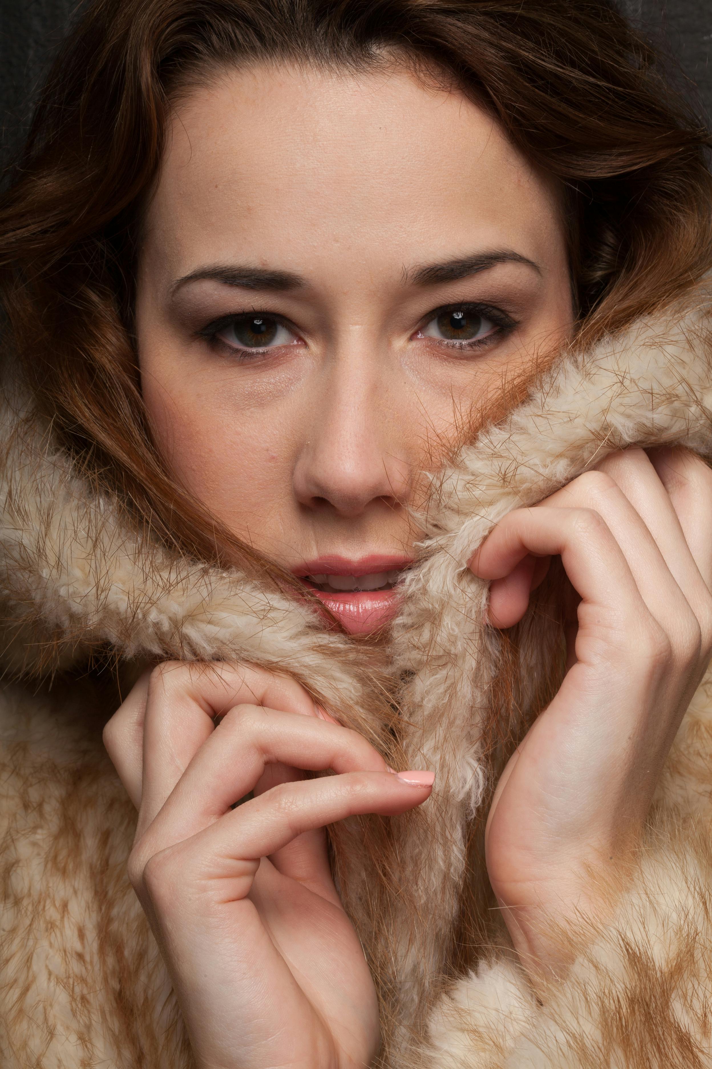 Close-up portrait of an elegant woman wrapped in a fur coat showcasing beauty and fashion.