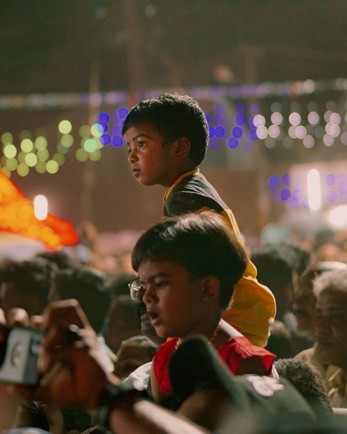 Free Children on shoulders enjoy a vibrant nighttime concert festival. Stock Photo