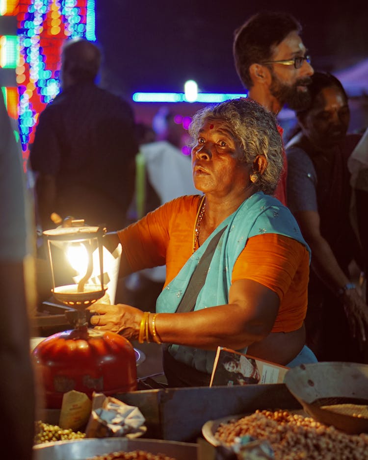 Elderly Woman In A Traditional Dress Holding A Lantern At The Market 