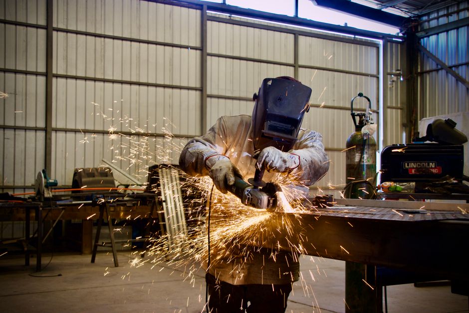 Welder using a grinder in a workshop, sparks flying, Lampa, Chile.