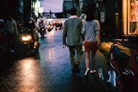 一对夫妇在夜晚的城市街道上漫步，四周环绕着摩托车与城市灯光