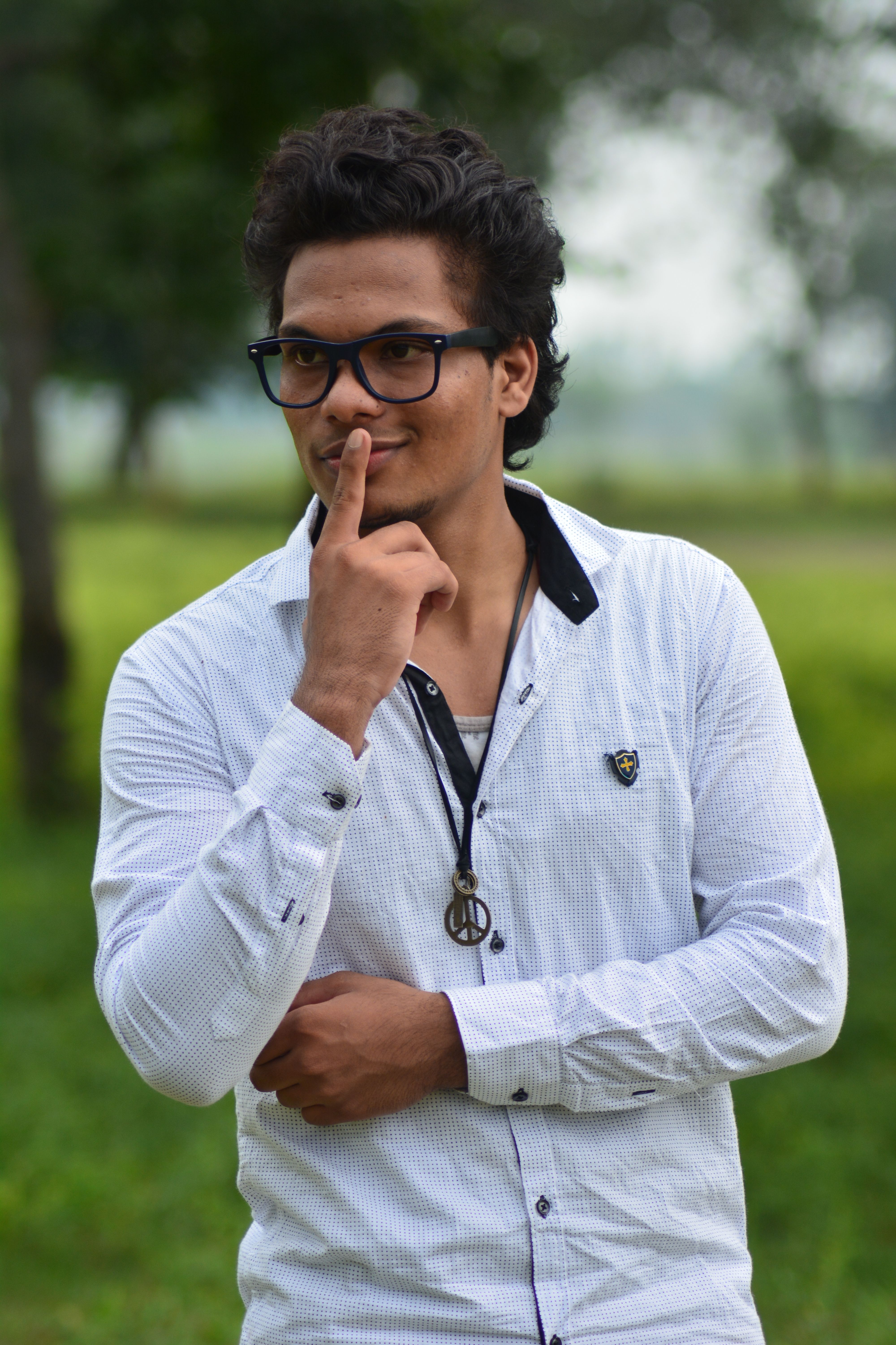 Portrait of a fashionable young man with eyeglasses in a park.