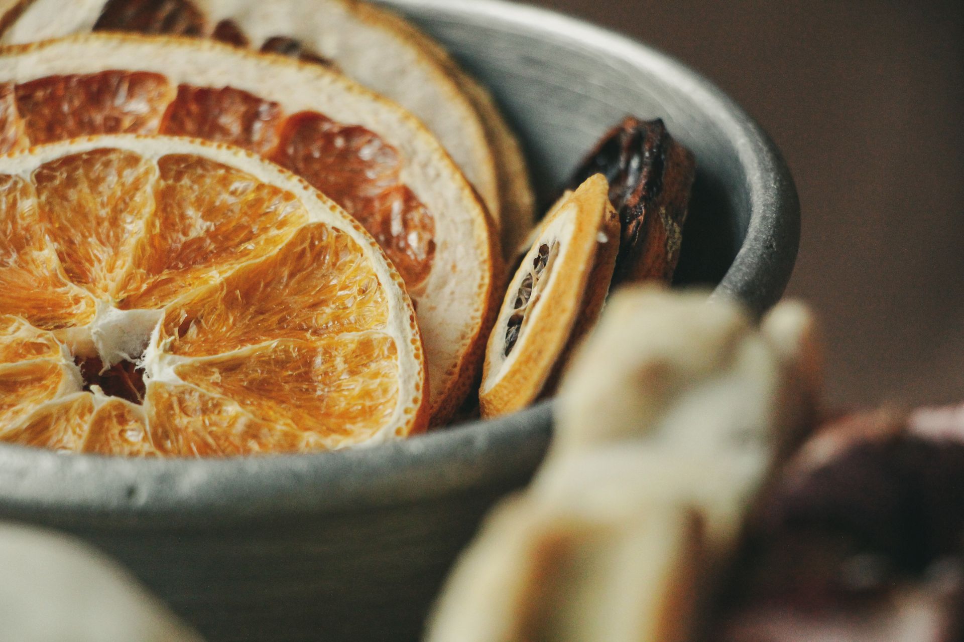 A close-up view of dried citrus slices in a rustic metal bowl, showcasing texture and detail.
