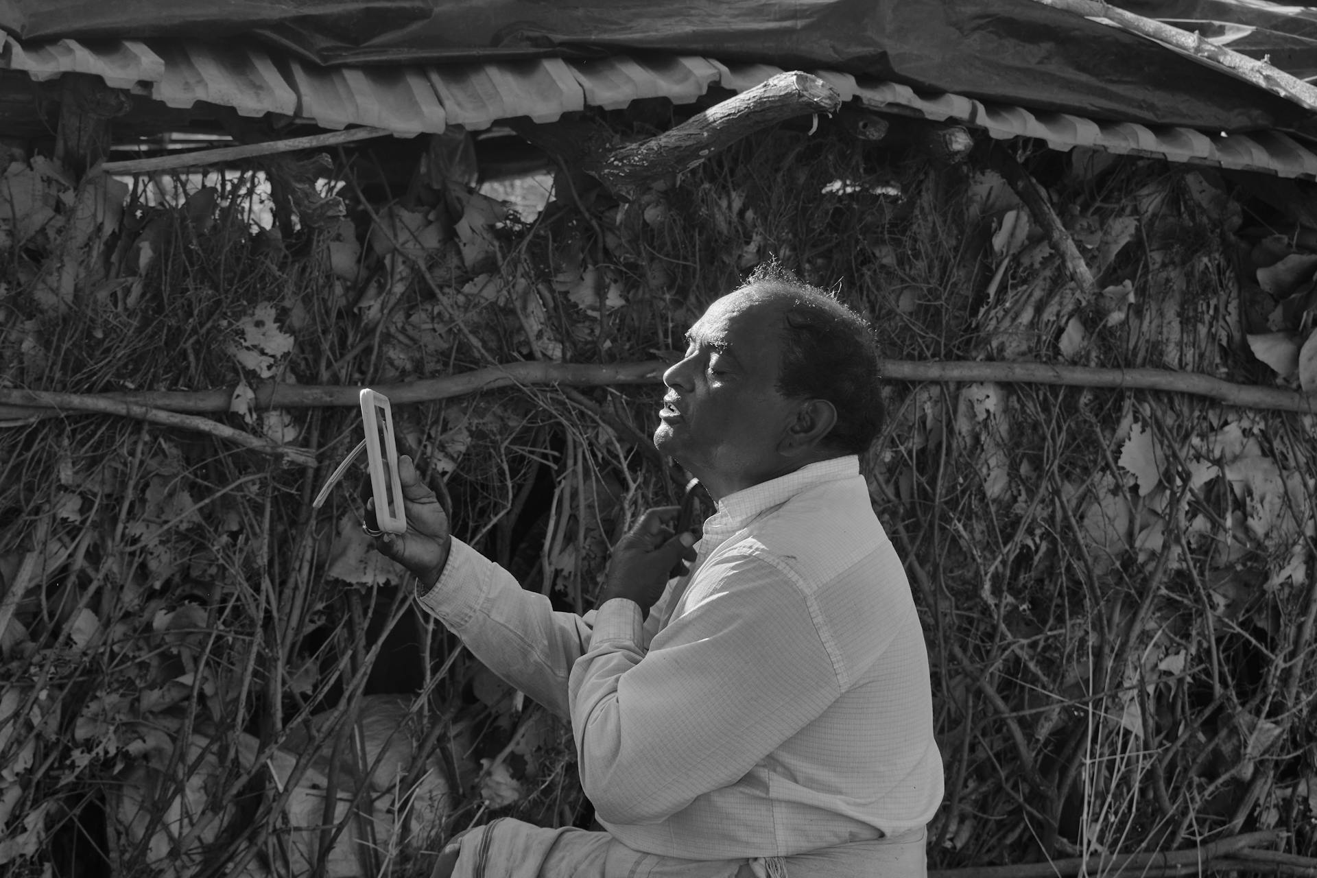 Black and white portrait of a man using a phone in rural Palanpur, India