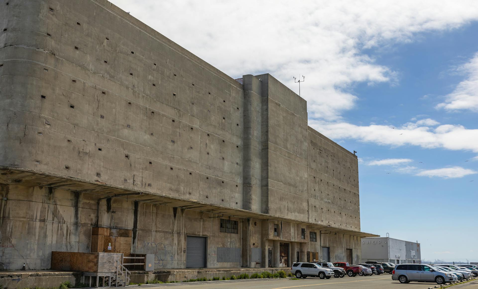 Concrete warehouse exterior with parked cars in Richmond, clear blue sky.