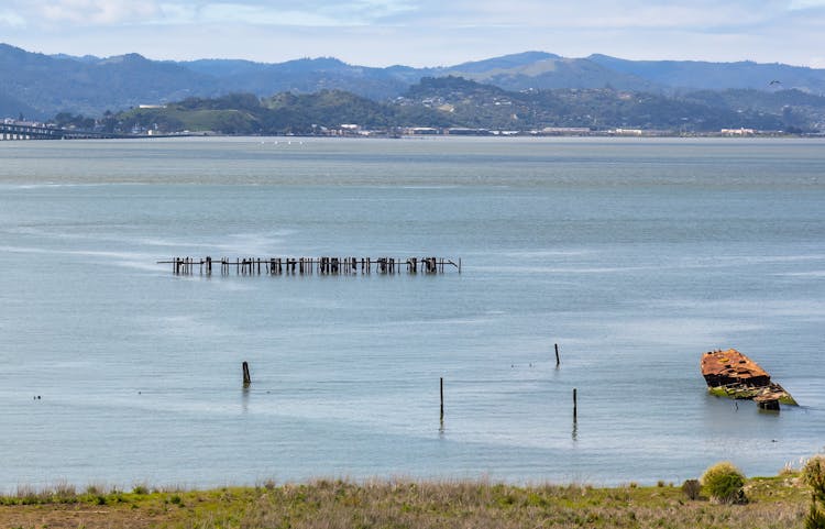 A Half Sunken Boat On The Shore In A Bay 