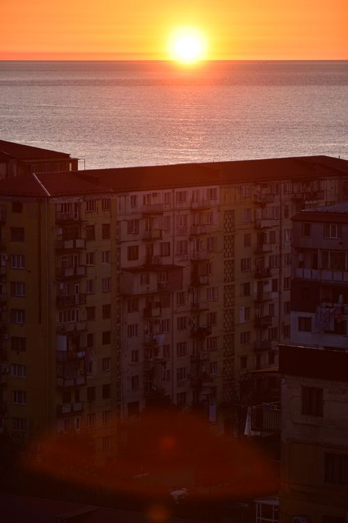 Free Captivating sunrise illuminating residential buildings by the ocean. Stock Photo