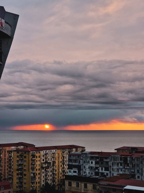 Free High-rise apartments overlooking a serene ocean sunset with a dramatic cloudscape. Stock Photo