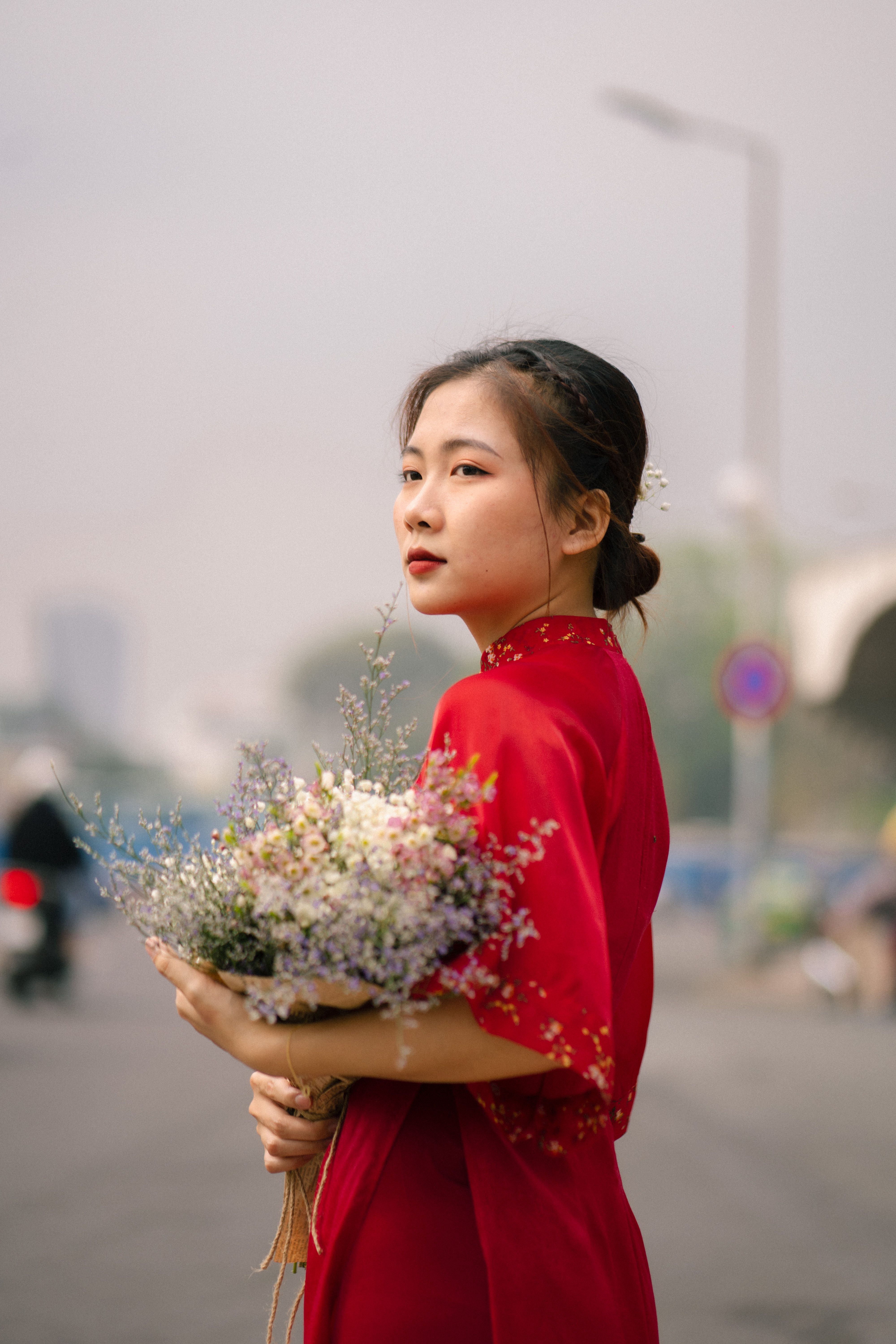 Young Woman Holding Flowers in Red Dress Outdoors · Free Stock Photo