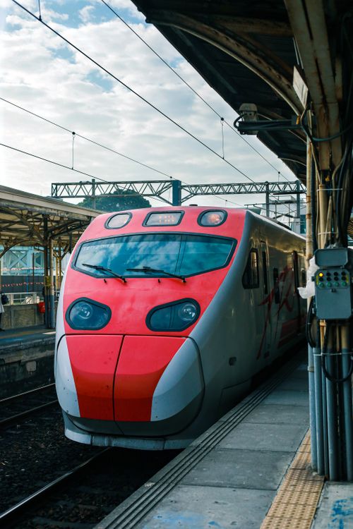 Free A bright red modern train awaits departure at a bustling urban railway station, showcasing advanced rail transportation. Stock Photo