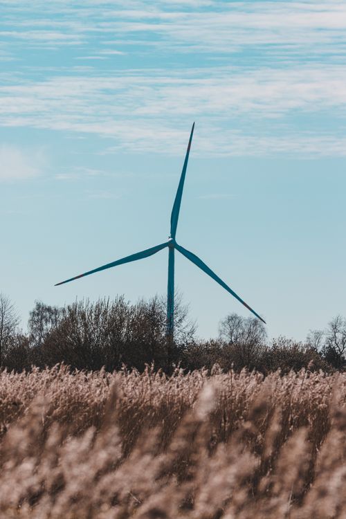 Free A wind turbine stands tall against a clear sky in a rural field, representing renewable energy. Stock Photo