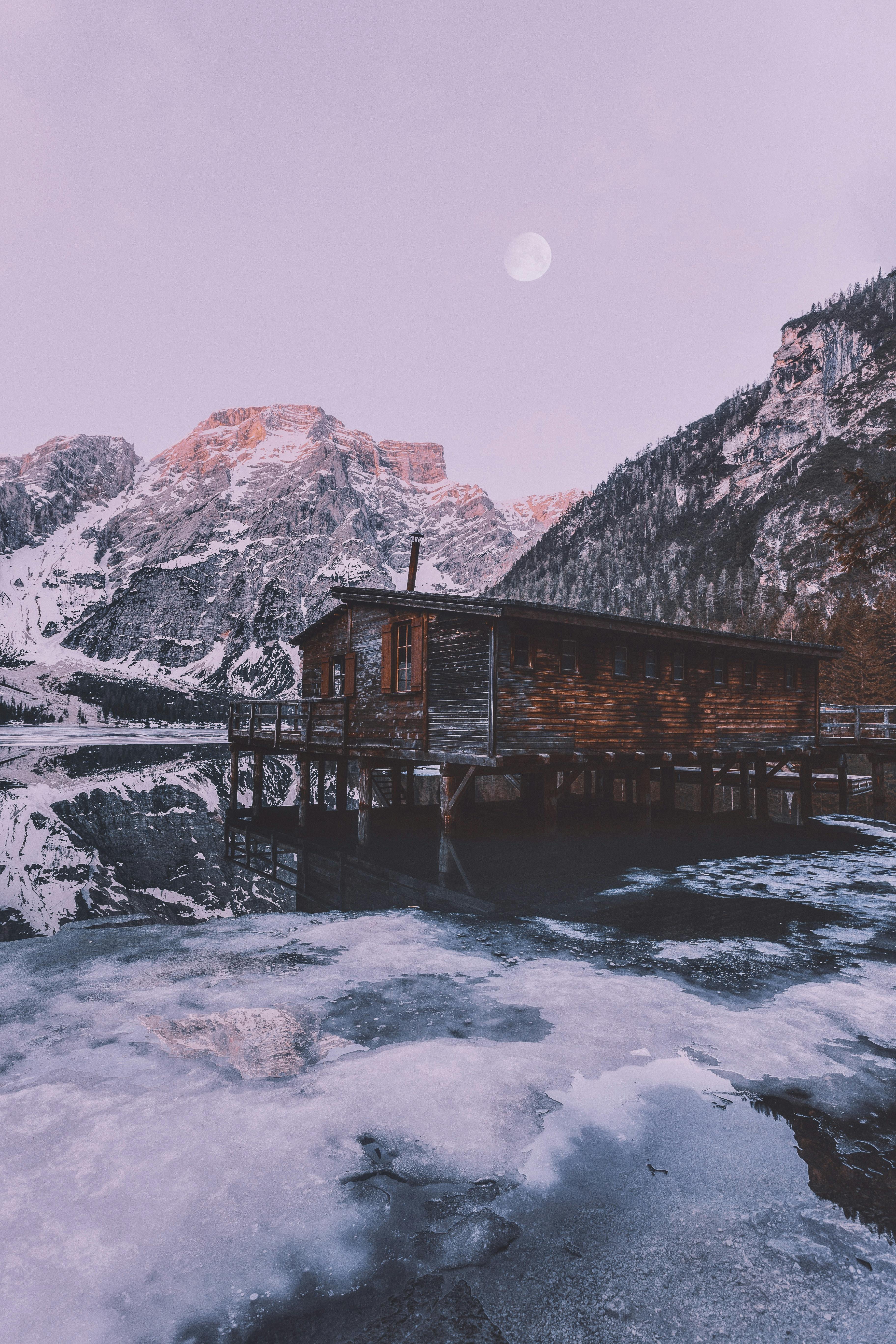 brown wooden house near snow covered mountain