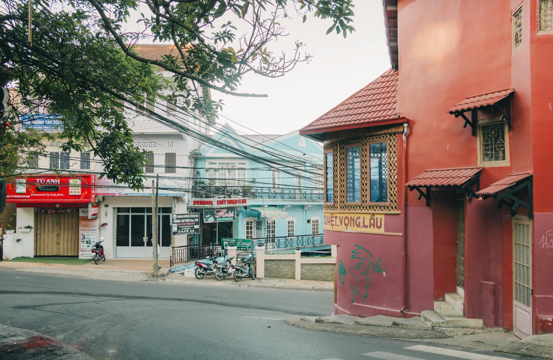 Quaint street scene in Vietnam featuring colorful architectural buildings and motorcycles.