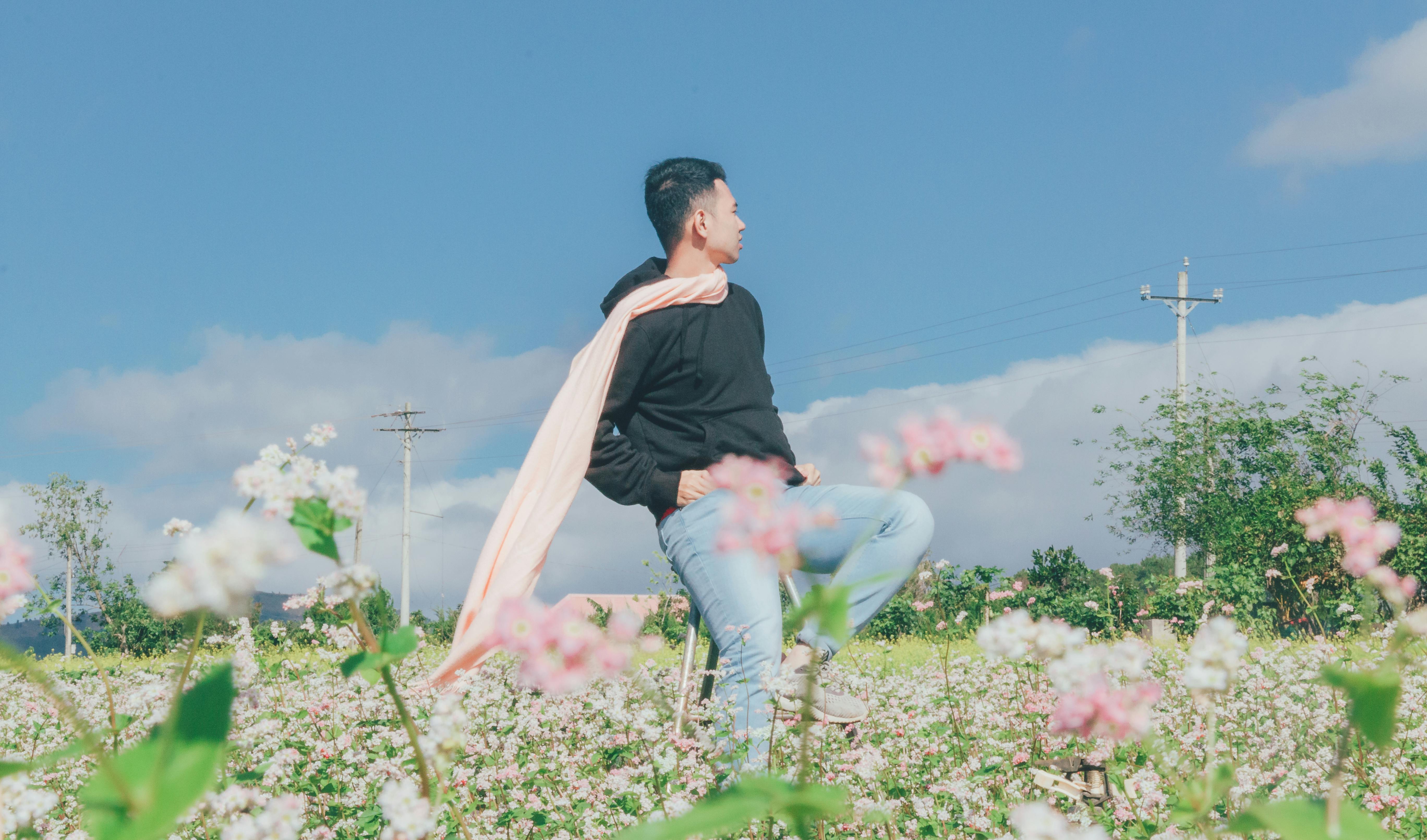 Man Sitting on Chair Surrounded by Flowers · Free Stock Photo