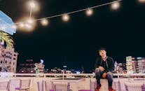 城市夜景中，一名男子站在屋顶上