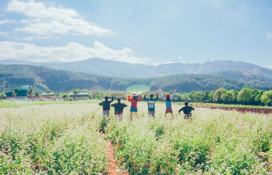 A joyful group of people in a picturesque rural field with mountains in the background.