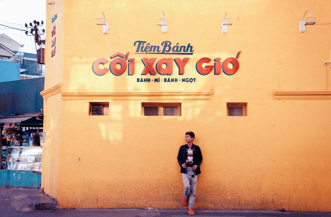 Phtoto of Man Leaning on Tiem Banh Building's Wall
