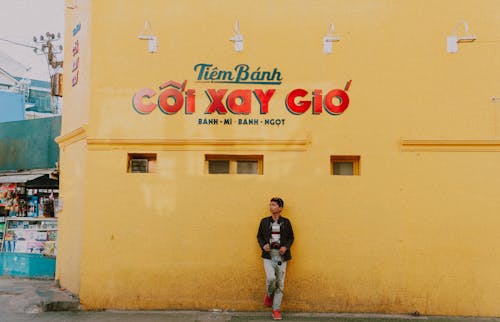Man Standing Beside Yellow Concrete Building