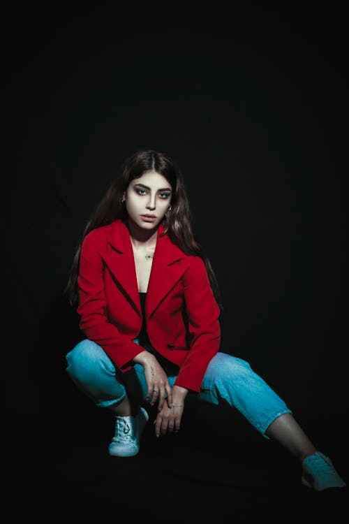 Woman in Red Coat Posing on Black Background