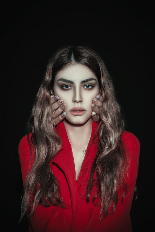 Hands on Face of Woman in Red Coat