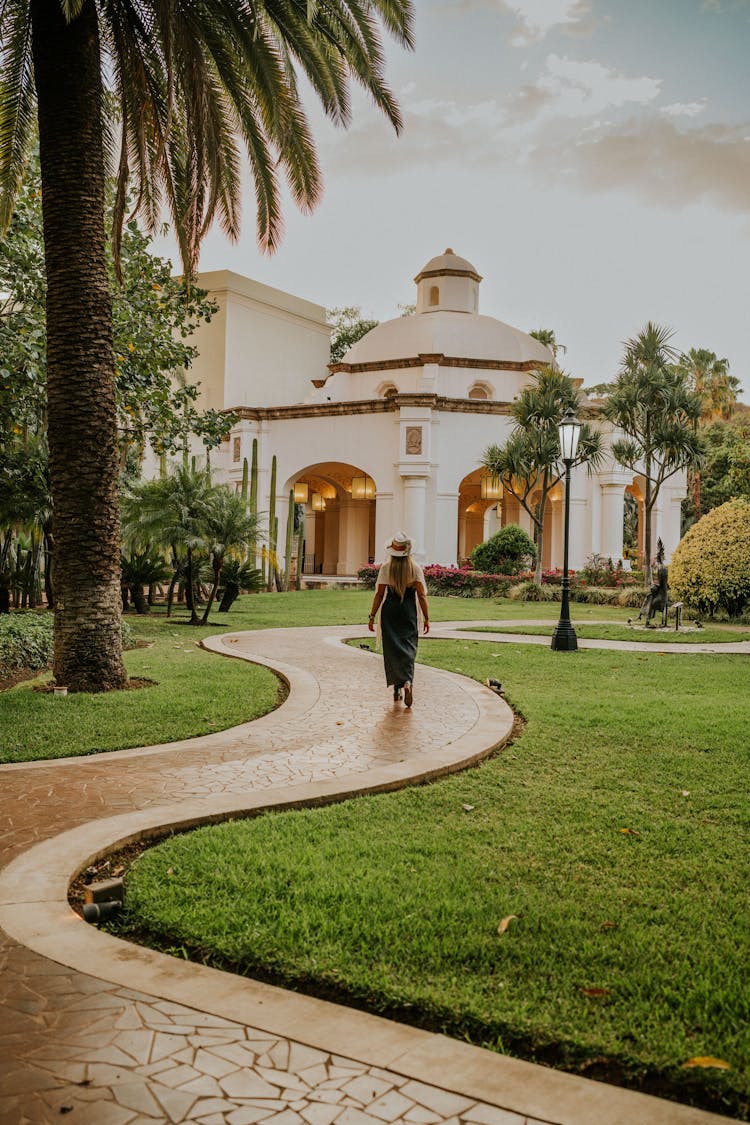 Woman Walking In Garden With Building