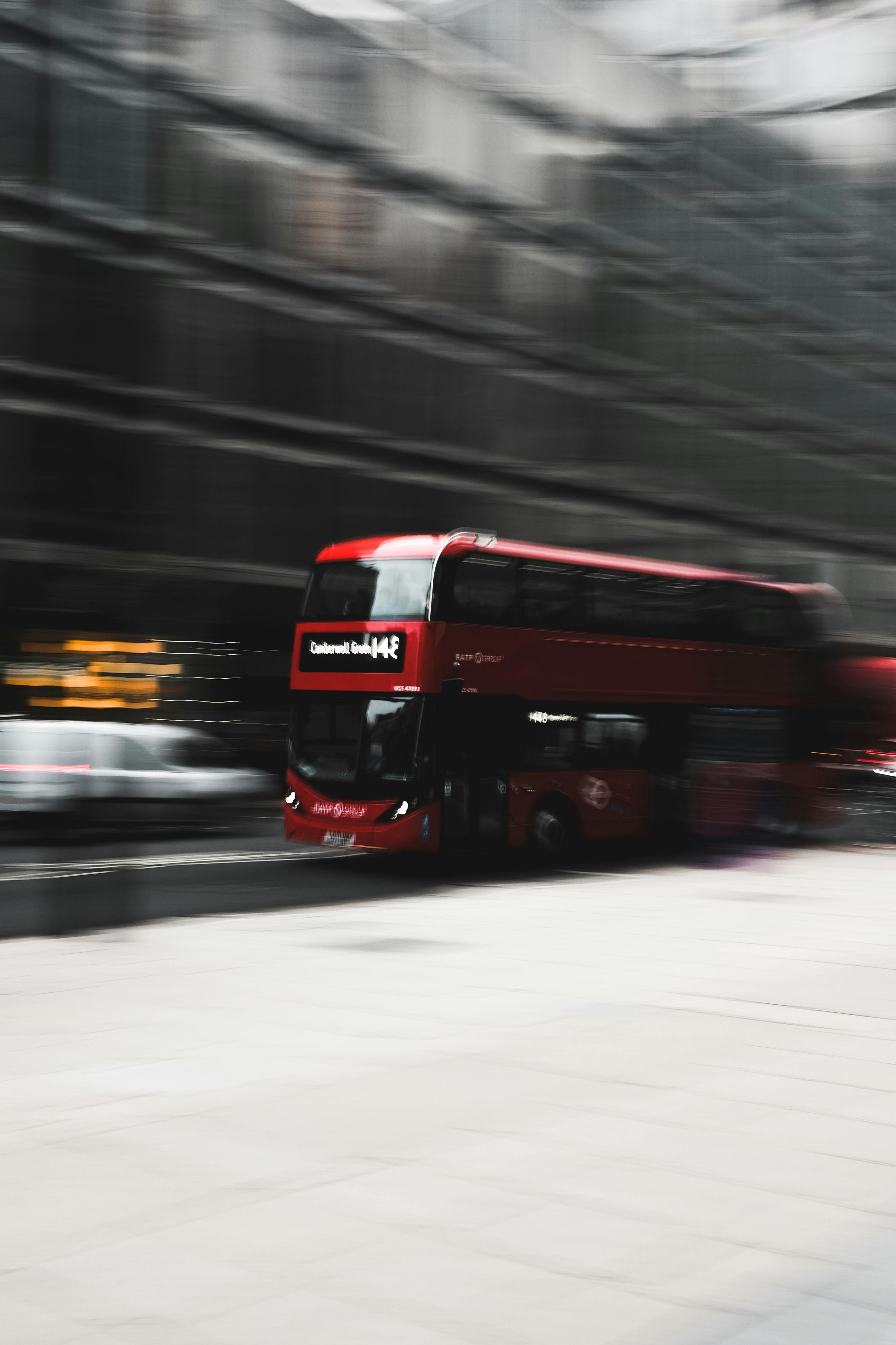 Blurred motion shot of a red double-decker bus speeding down a city street.
