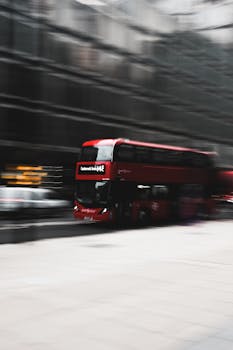 Blurred motion shot of a red double-decker bus speeding down a city street.