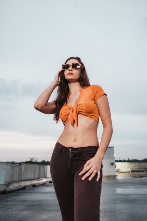 Woman Standing in Orange Top and Sunglasses
