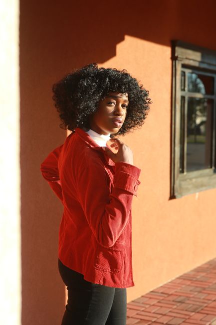Portrait of a fashionable black woman in a red jacket enjoying a sunny day.