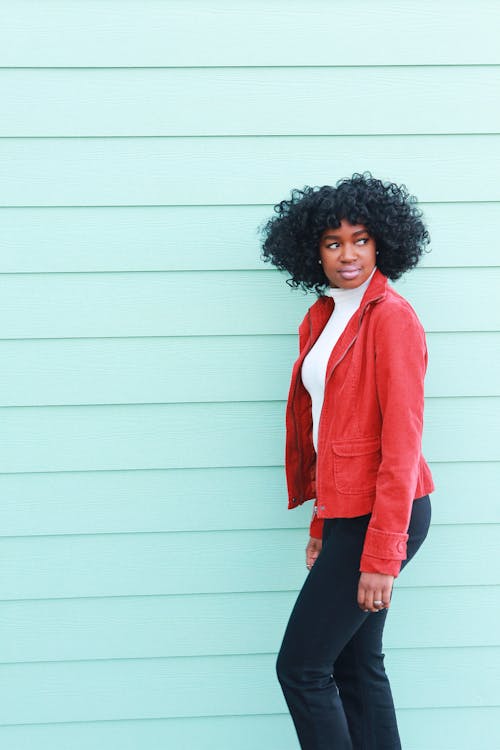 Woman in Red Blazer Standing Beside Light-blue Wall Looking Sideways